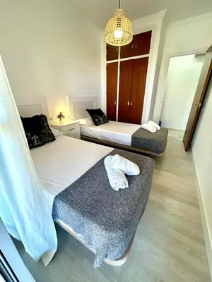 a bedroom with two beds and a chandelier at Gatu VILLA ANTILLAS parking gratis preferentemente mayores de 25 años y familias in El Puerto de Santa María