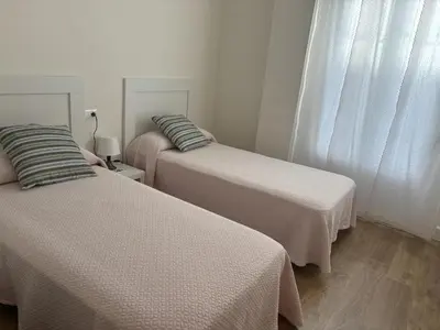two beds in a room with white walls at Casa Luada in Sanlúcar de Barrameda