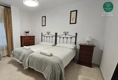 a bedroom with two beds and a dresser with a lamp at Mirador del Castillo by Sanlúcar Housing in Sanlúcar de Barrameda