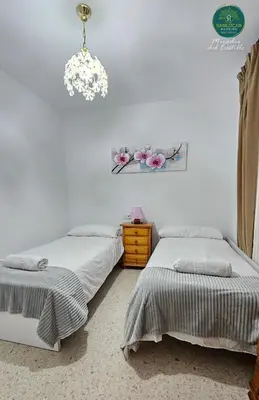 two beds in a bedroom with a chandelier at Mirador del Castillo by Sanlúcar Housing in Sanlúcar de Barrameda
