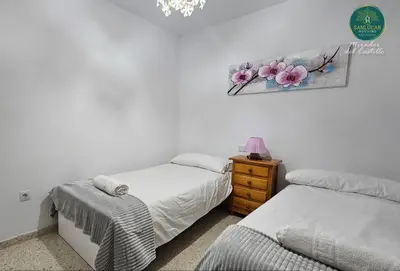 a bedroom with two beds and a painting on the wall at Mirador del Castillo by Sanlúcar Housing in Sanlúcar de Barrameda