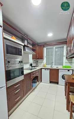 a large kitchen with wooden cabinets and white appliances at Mirador del Castillo by Sanlúcar Housing in Sanlúcar de Barrameda
