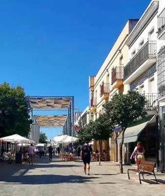 a street with people walking down a street with buildings at Chipiona Center in Chipiona
