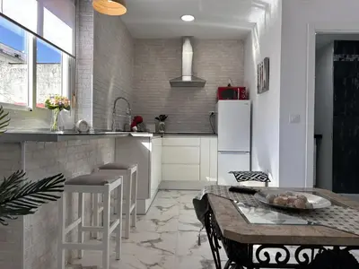 a kitchen with a table and a white refrigerator at Dante Suite - Ole Solutions in Jerez de la Frontera