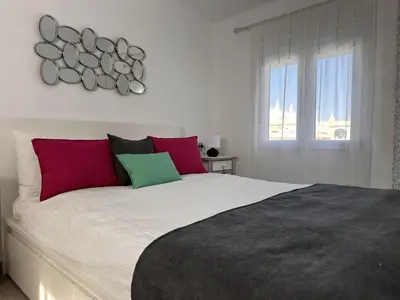 a bedroom with a large bed with red and green pillows at Dante Suite - Ole Solutions in Jerez de la Frontera