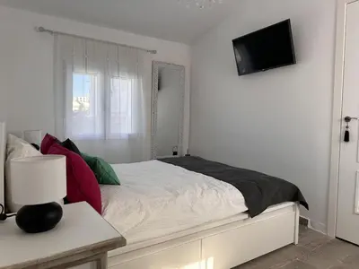 a white bedroom with a bed with a tv on the wall at Dante Suite - Ole Solutions in Jerez de la Frontera