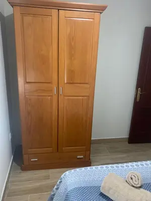 a bedroom with a wooden cabinet and a bed at Apartamento Turístico en Chiclana de la Frontera in Chiclana de la Frontera
