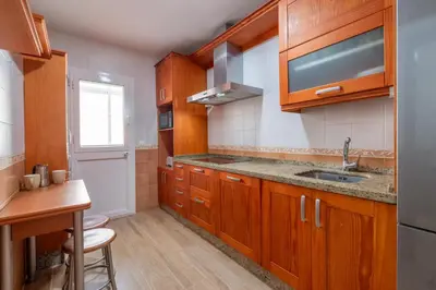 a kitchen with wooden cabinets and a sink at Apartamento Turístico en Chiclana de la Frontera in Chiclana de la Frontera