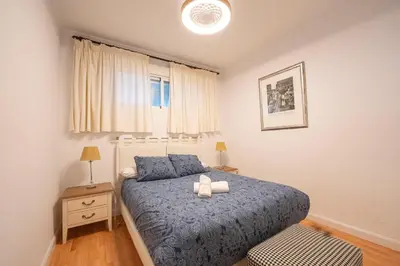 a bedroom with a bed with a blue comforter and a window at Alta Mar Playa Victoria in Cádiz