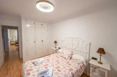 a white bedroom with a bed and a table at Alta Mar Playa Victoria in Cádiz