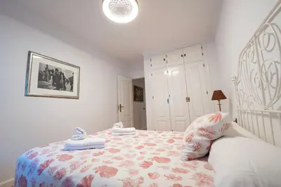 a bedroom with a bed with a floral bedspread at Alta Mar Playa Victoria in Cádiz