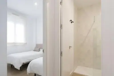a white bedroom with a bed and a shower at Apartoyou - El Patio Centro in El Puerto de Santa María