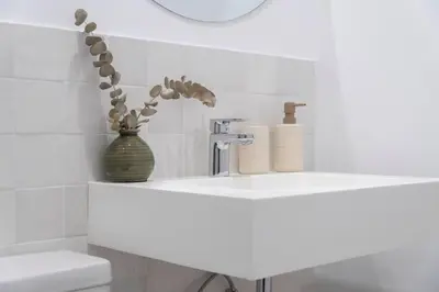 a white bathroom with a sink and a vase with flowers at Apartoyou - El Patio Centro in El Puerto de Santa María