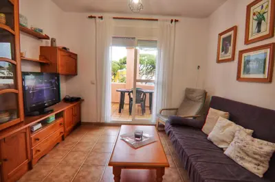 a living room with a couch and a tv at Apartamento Familiar junto a Playa La Barrosa in Novo Sancti Petri