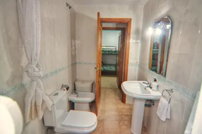 a bathroom with a toilet and a sink and a mirror at Apartamento Familiar junto a Playa La Barrosa in Novo Sancti Petri