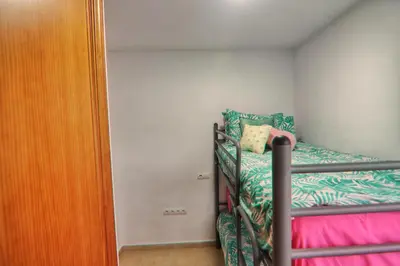 a small bedroom with a bunk bed and a closet at Apartamento Familiar junto a Playa La Barrosa in Novo Sancti Petri