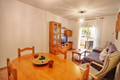 a living room with a table and a couch at Apartamento Familiar junto a Playa La Barrosa in Novo Sancti Petri