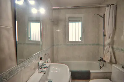a bathroom with a tub and a sink and a mirror at Apartamento Familiar junto a Playa La Barrosa in Novo Sancti Petri