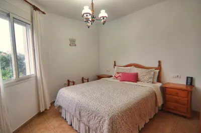 a bedroom with a bed and a window and a chandelier at Apartamento Familiar junto a Playa La Barrosa in Novo Sancti Petri
