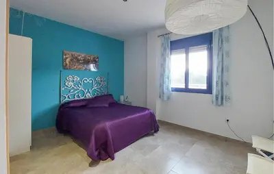 a bedroom with a purple bed and a blue wall at 4 Bedroom Awesome Apartment In Chipiona in Chipiona