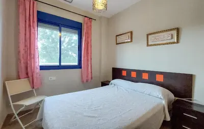 a bedroom with a bed and a window and a chair at 4 Bedroom Awesome Apartment In Chipiona in Chipiona