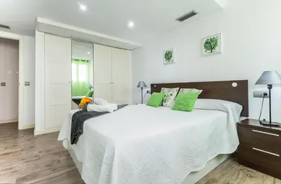 a bedroom with a large white bed with green pillows at Apartments Vistas Mar Bahia in Cádiz