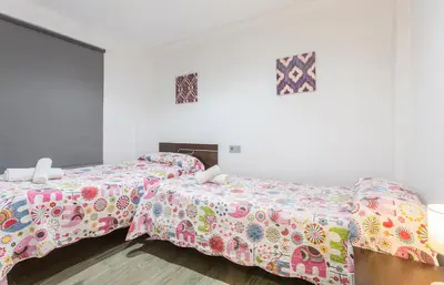 two beds in a white room with colorful sheets at Apartments Vistas Mar Bahia in Cádiz