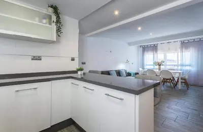 a kitchen with white cabinets and a living room at Apartments Vistas Mar Bahia in Cádiz