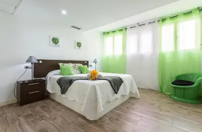 a bedroom with green curtains and a bed with a table at Apartments Vistas Mar Bahia in Cádiz