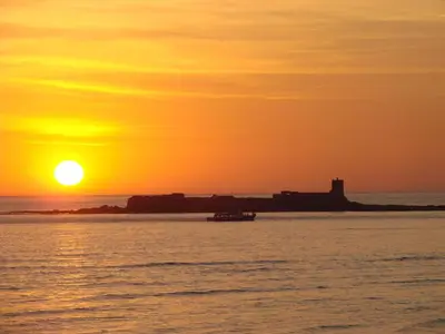 a sunset over a body of water with a lighthouse at Brisamar Golf Novo Sancti Petri House, Open Pool over the year in Chiclana de la Frontera