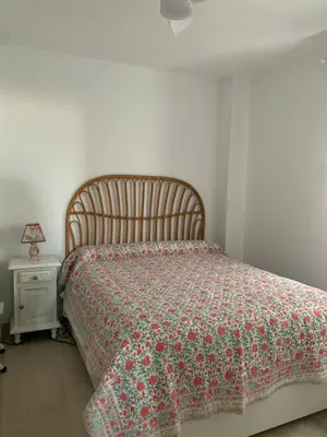 a bedroom with a bed with a floral bedspread and a night stand at Arenas de Doñana in Sanlúcar de Barrameda