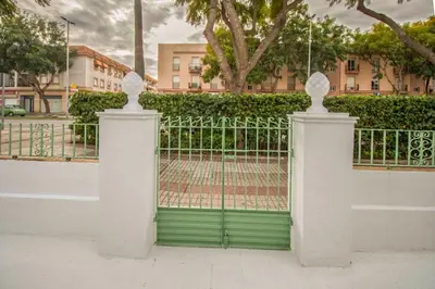 a white fence with a green gate in front of a building at Villa Emilia in Sanlúcar de Barrameda