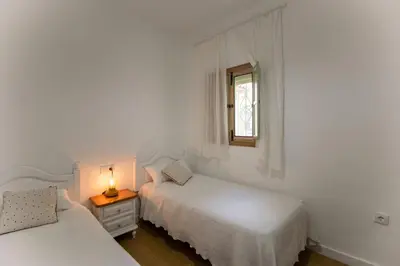 two beds in a white room with a window at Villa Emilia in Sanlúcar de Barrameda