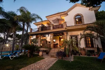 a large house with palm trees in front of it at Hotel Azalea Playa in Chiclana de la Frontera