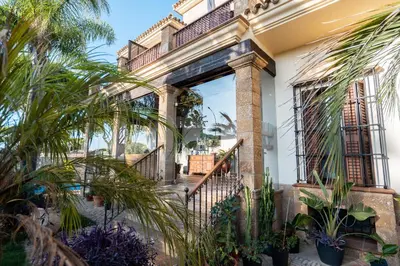 a house with palm trees in the courtyard at Hotel Azalea Playa in Chiclana de la Frontera
