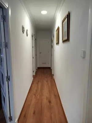 a hallway with white walls and a wooden floor at Ave 26, piso junto playa in Cádiz