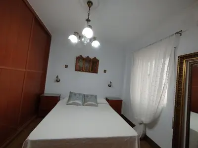 a bedroom with a white bed and a chandelier at Ave 26, piso junto playa in Cádiz