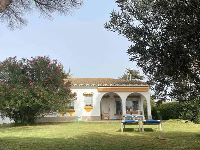 a small white house with a bench in the yard at Casa 77, la playa más bonita a 150 metros in Conil de la Frontera