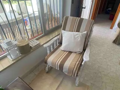 a chair with a pillow sitting in front of a window at Casa 77, la playa más bonita a 150 metros in Conil de la Frontera
