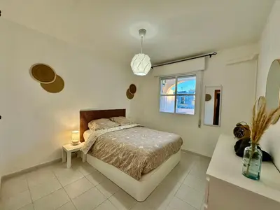 a bedroom with a bed and a table and a window at Piso Bahia in Chiclana de la Frontera