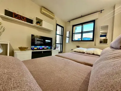 a room with two beds and a flat screen tv at Piso Bahia in Chiclana de la Frontera