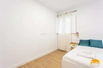 a bedroom with a white bed with blue pillows at Casa del Marinero by LiveWork in Cádiz
