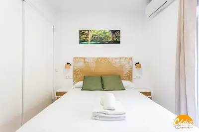 a bedroom with a white bed with green pillows at Casa del Marinero by LiveWork in Cádiz