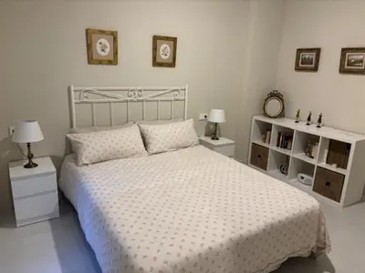 a white bedroom with a bed and two night stands at Apartamento la Porvera in Jerez de la Frontera