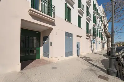 a white building with green doors and a sidewalk at Bajamar Deluxe in El Puerto de Santa María