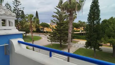 a balcony with a blue railing and palm trees at Apartamento en Playa Ballena III in Rota