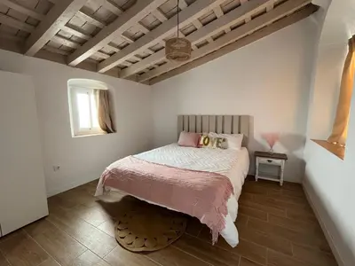 a bedroom with a bed with pink sheets and a window at El Encanto de Jerez in Jerez de la Frontera