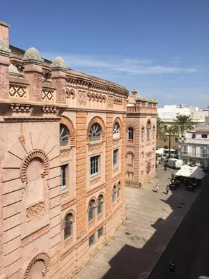 a large brick building with people walking in front of it at Vista Plaza Falla in Cádiz