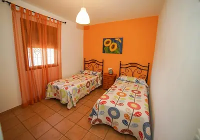 two beds in a room with orange walls at Casa Ana Mari in Conil de la Frontera