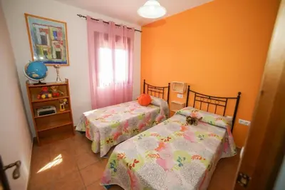 two beds in a room with orange walls at Casa Ana Mari in Conil de la Frontera